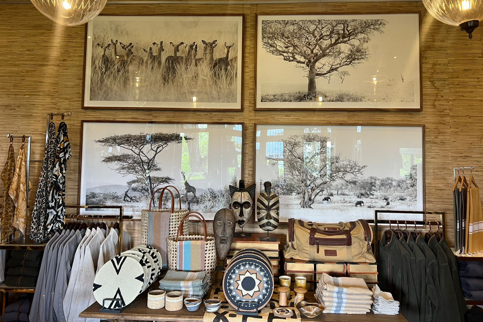 Interior of a store with clothing racks, bags, and framed artwork on the wall.